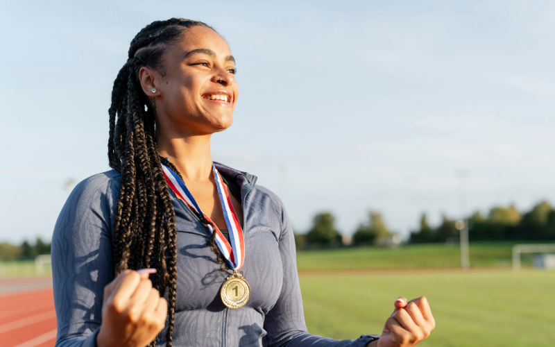 En kvinna i löparkläder bär en medalj på bröstet och ler stort.