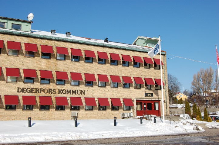 Nämndhuset i Degerfors fotograferat från Medborgarplatsen. Degerfors kommuns flagga med kommunvapnet vajar i vinden och det är snö på marken.