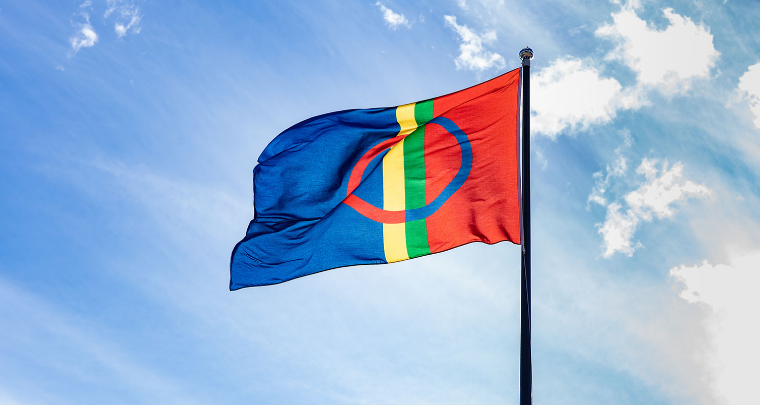 En bild på den samiska flaggan mot en blå himmel