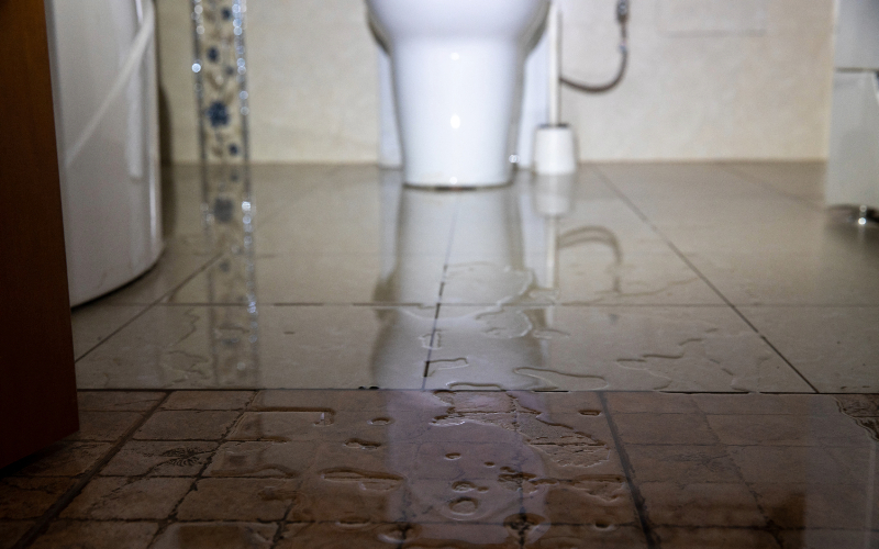 Vatten läcker ut på golvet på en toalett.