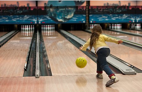 Ett barn bowlar i en bowlinghall.
