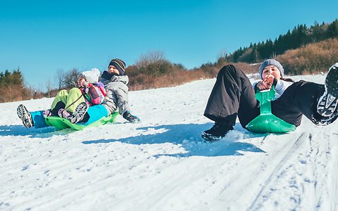 Tre barn åker pulka i snön.